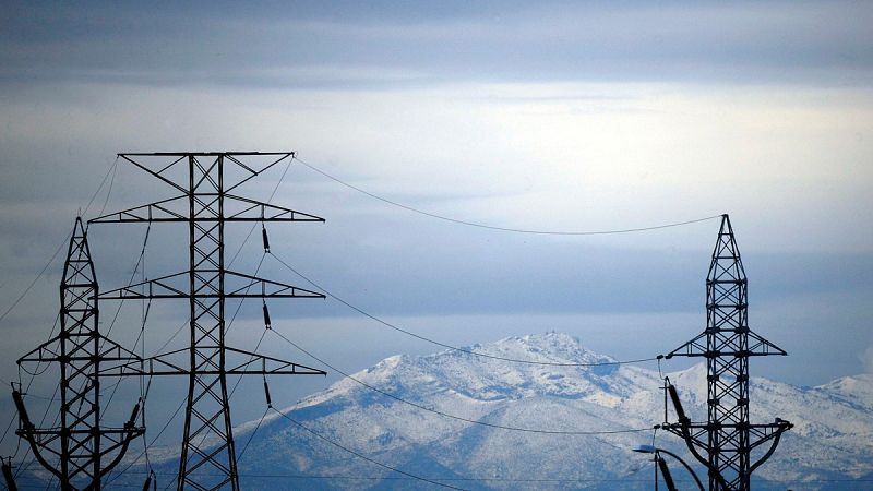 Torres de alta tensión se recortan contra las montañas nevadas que rodean la ciudad de Valencia