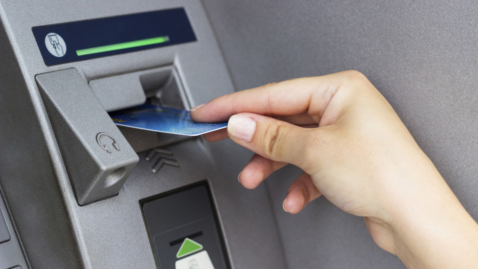 Una persona introduce su tarjeta de débito en un cajero automático
