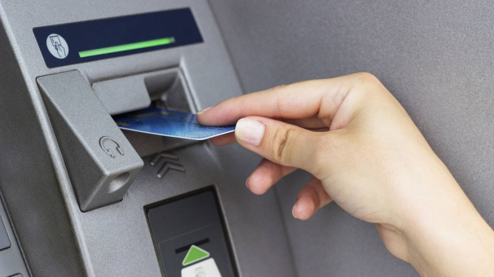 Una persona introduce su tarjeta de débito en un cajero automático