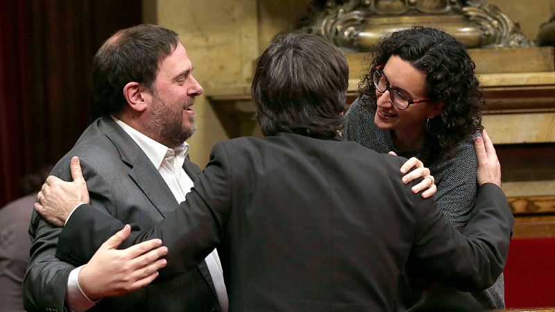El nuevo presidente de la Generalitat, Carles Puigdemont es felicitado por los lideres de ERC, Oriol Junqueras y Marta Rovira, tras ser elegido en el Parlament de Cataluña.