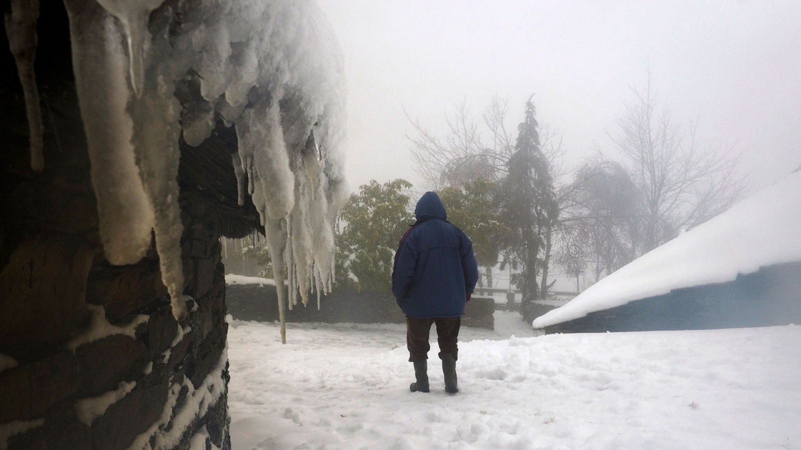 Un hombre camina por las nevadas calles del pueblo de montaña de O Cebreiro, en Lugo