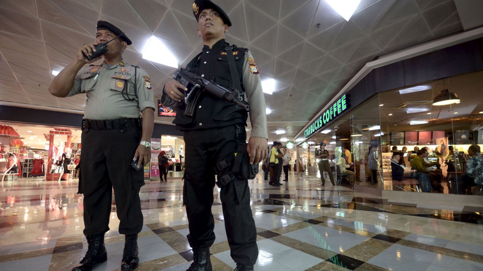 Indonesian police officer holds a weapon as he stands guard inside Ratu Indah Mall in Makassar