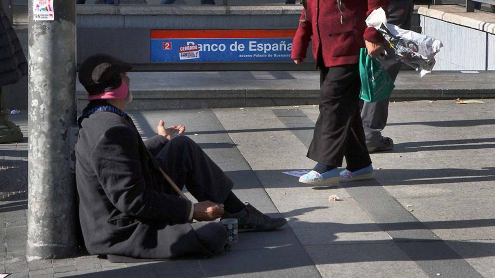 Un anciano mendiga junto a una salida del Metro en el centro de Madrid