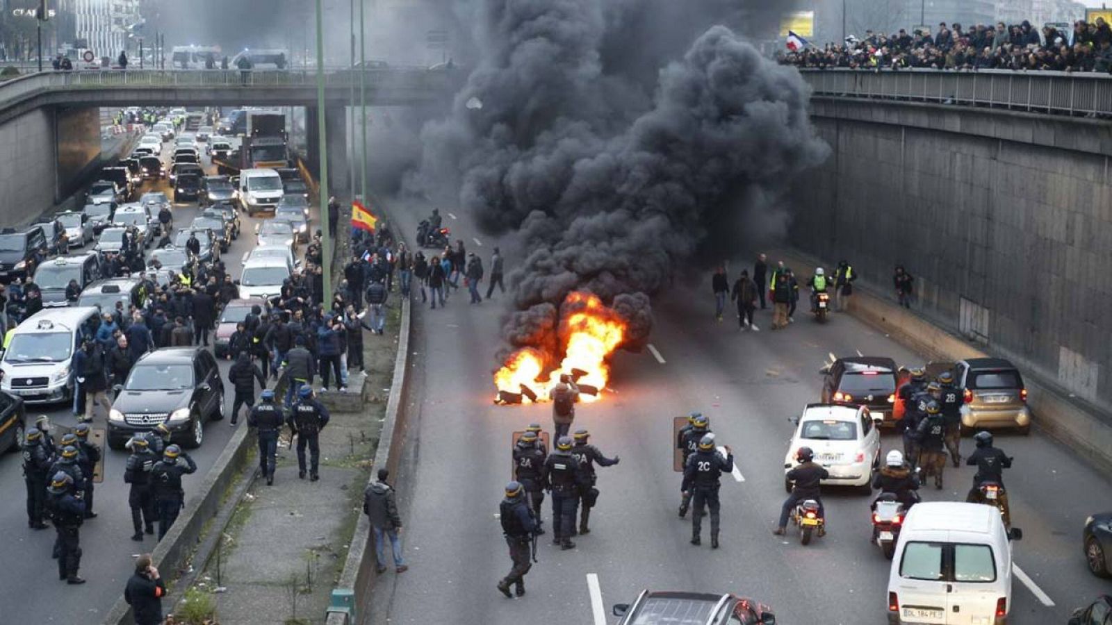 Policías antidisturbios tratan de disolver el bloqueo de los taxistas en la vía de circunvalación de París, a la altura de Porte Maillot