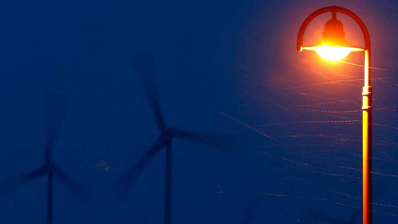 Una farola encendida delante de unos aerogeneradores