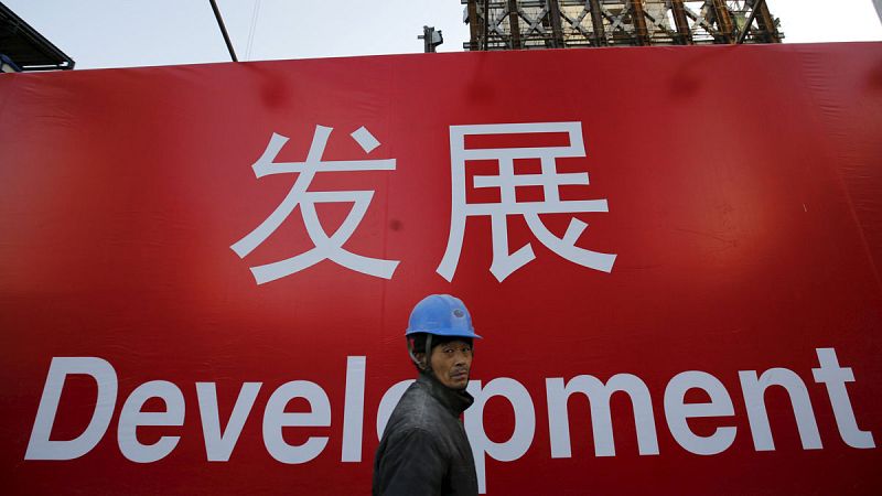 Un obrero pasa por delante de un cartel en el que se lee "desarrollo"