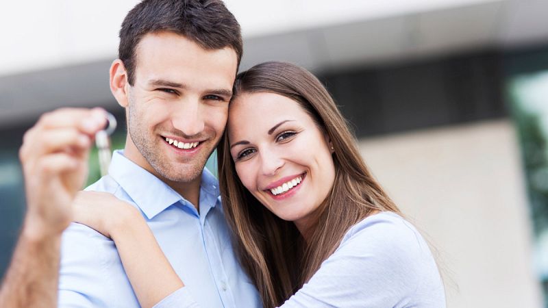 Una pareja de jóvenes con las llaves de una casa