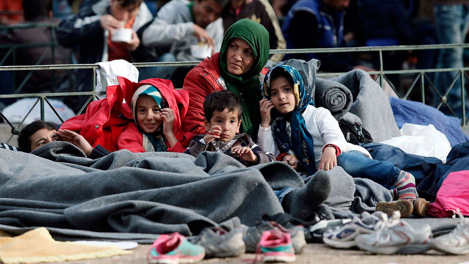 Una refugiada espera con varios niños en Atenas