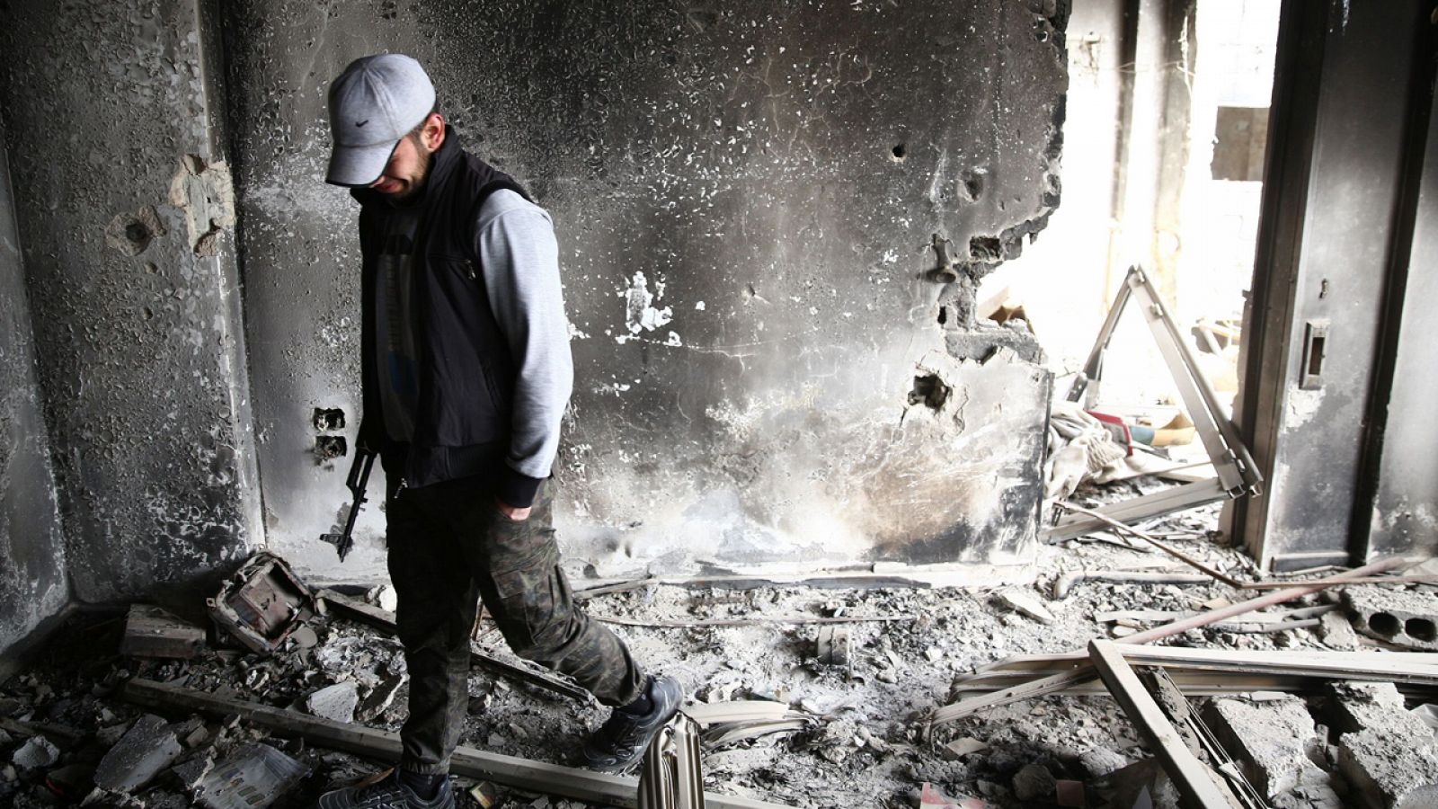 Un soldado sirio opositor camina sobre las ruinas de una vivienda destruida en Damasco