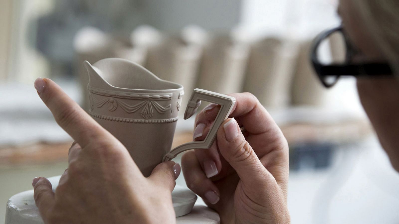 Una trabajadora pega el asa de una taza en una fábrica de Berlín