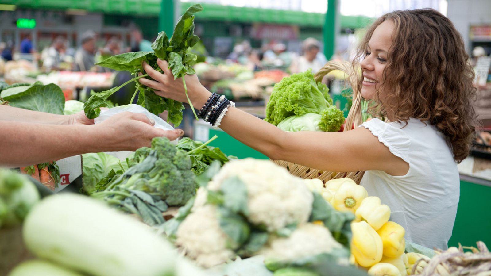 Una mujer compra verdura en un mercado