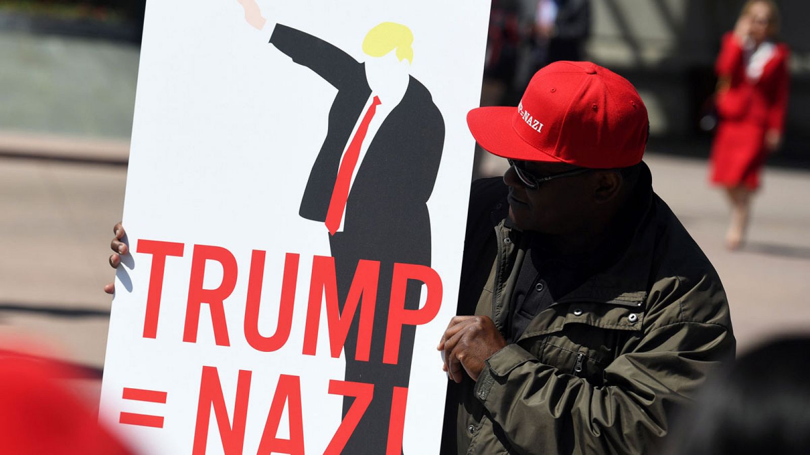 Un manifestante porta una pancarta contra Donald Trump frente al hotel en el que el magnate ha pronunciado un discurso.