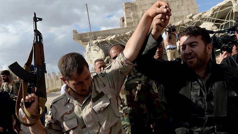Dos soldados sirios reaccionan a la llegada de un convoy militar ruso a una aldea cerca de Hama, Siria, el 4 de mayo de 2016. AFP PHOTO / Vasily MAXIMOV / MOY