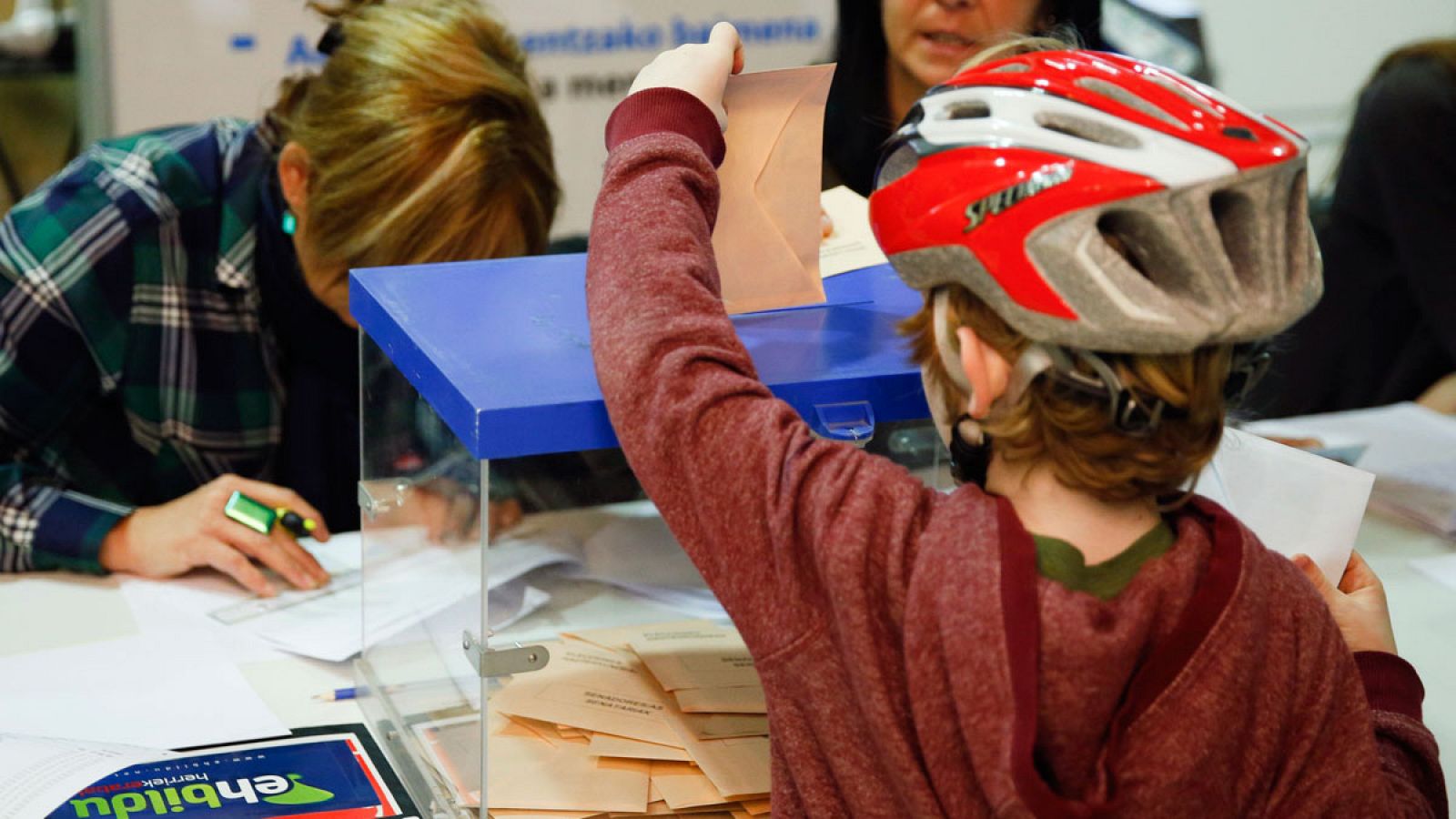 Un niño introduce la papeleta de sus padres en una urna de un colegio electoral de San Sebastián con motivo de las elecciones generales del 20D