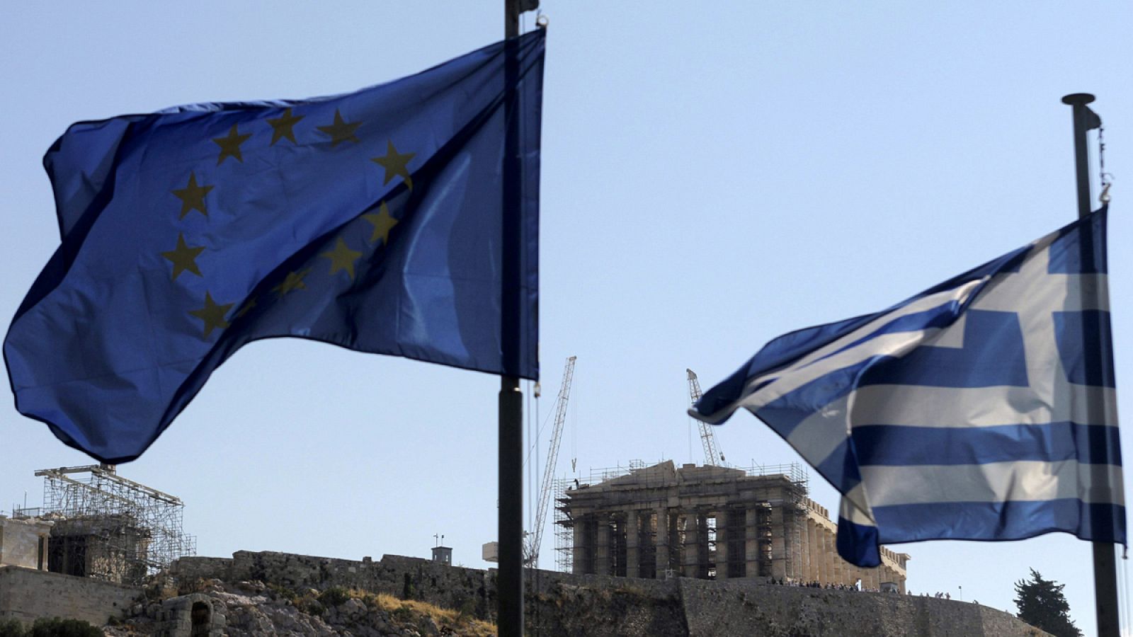 Una bandera griega y una de la Unión Europea ondean junto a la Acrópolis de Atenas