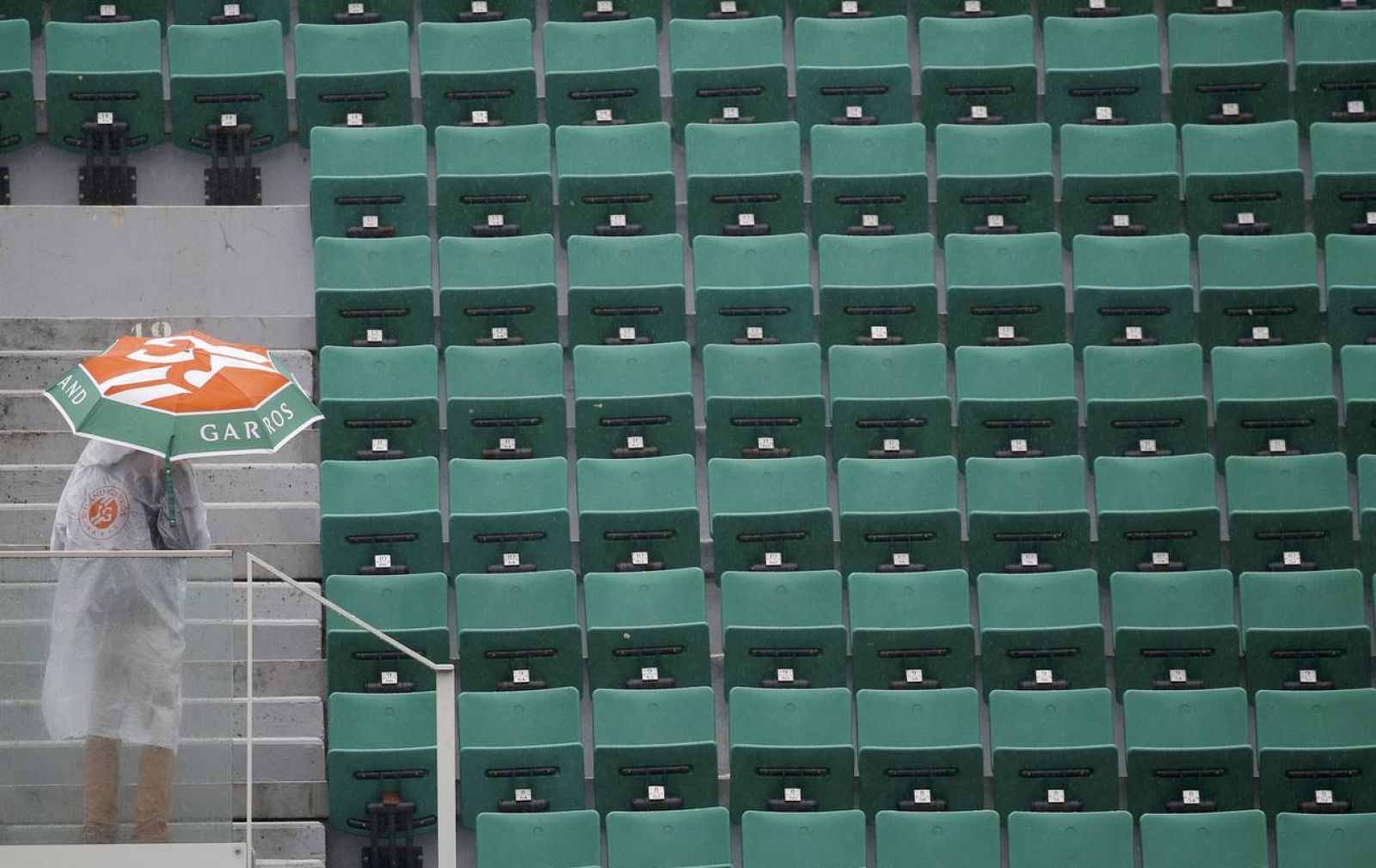 Un hombre se protege de la lluvia en el estadio central de Roland Garros este lunes. 