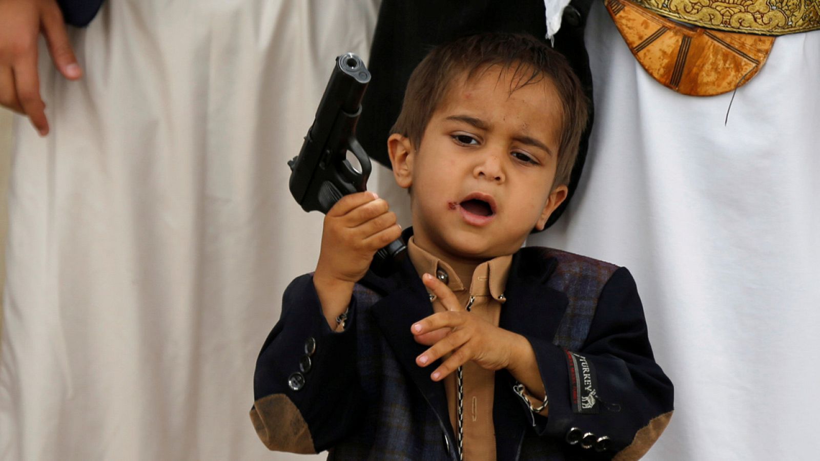Un niño sujeta la pistola de su padre en una concentración de hutíes en Sana