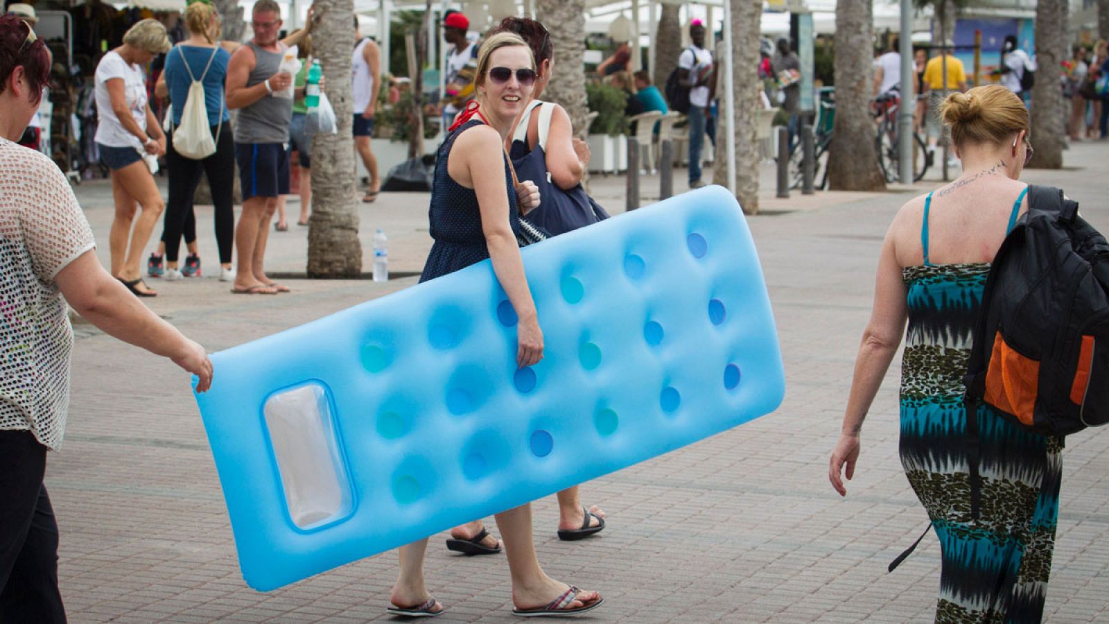 Una turista con una colchoneta se dirige a la playa en Palma de Mallorca