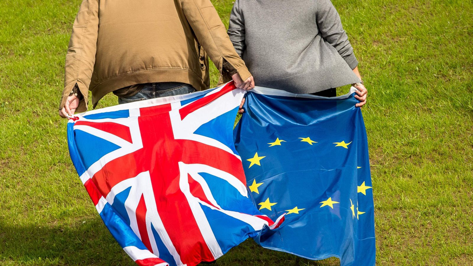 Dos personas portan una bandera del Reino Unido y otra de la Unión Europea