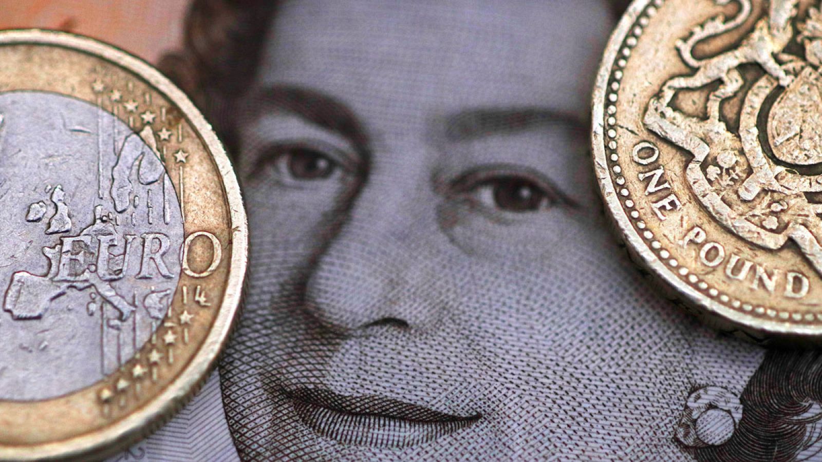 Una moneda de una libra y un euro sobre una ilustración de la reina de Inglaterra