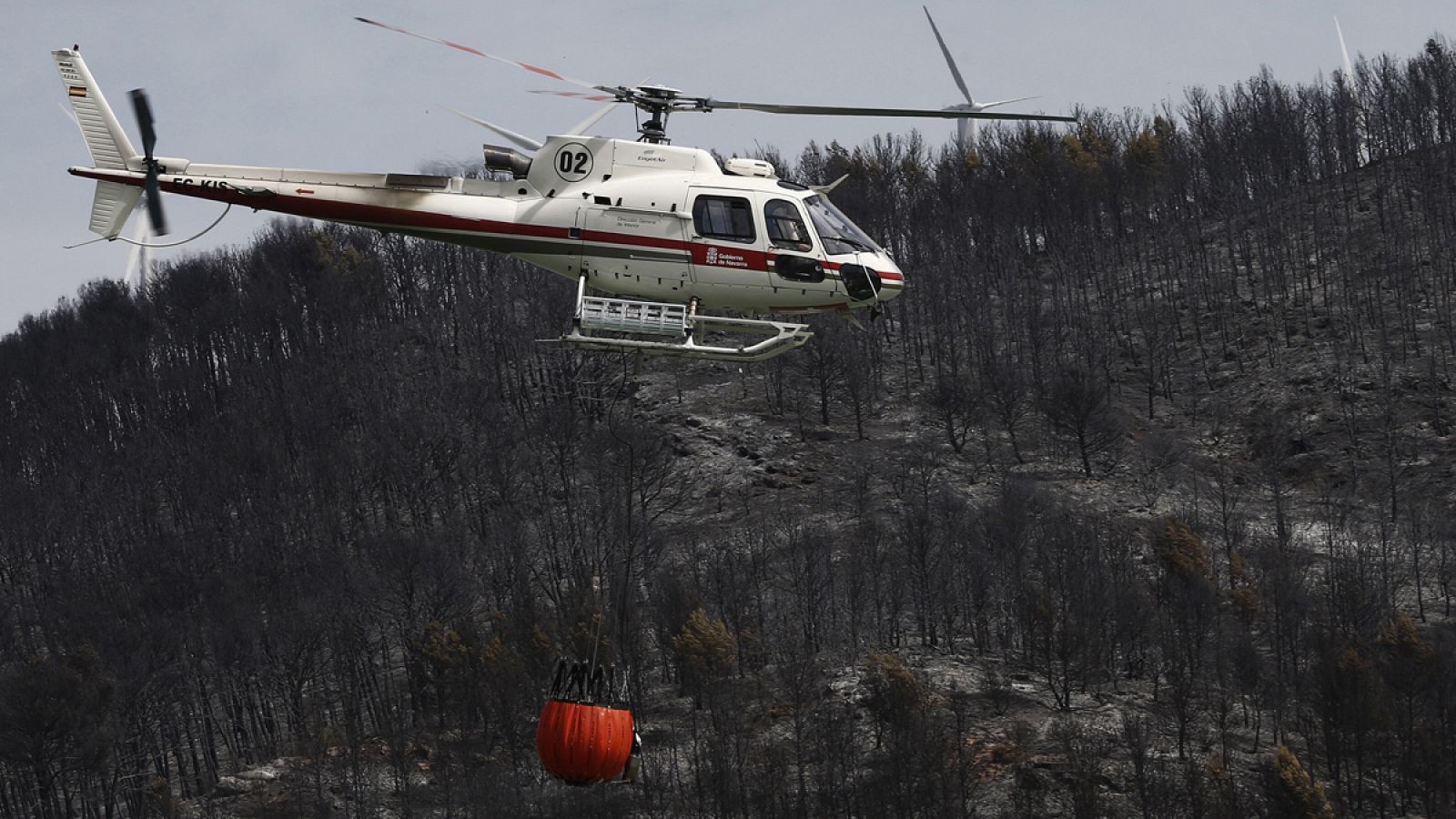 Un helicóptero enfría con agua la zona quemada en Trafalla, Navarra.