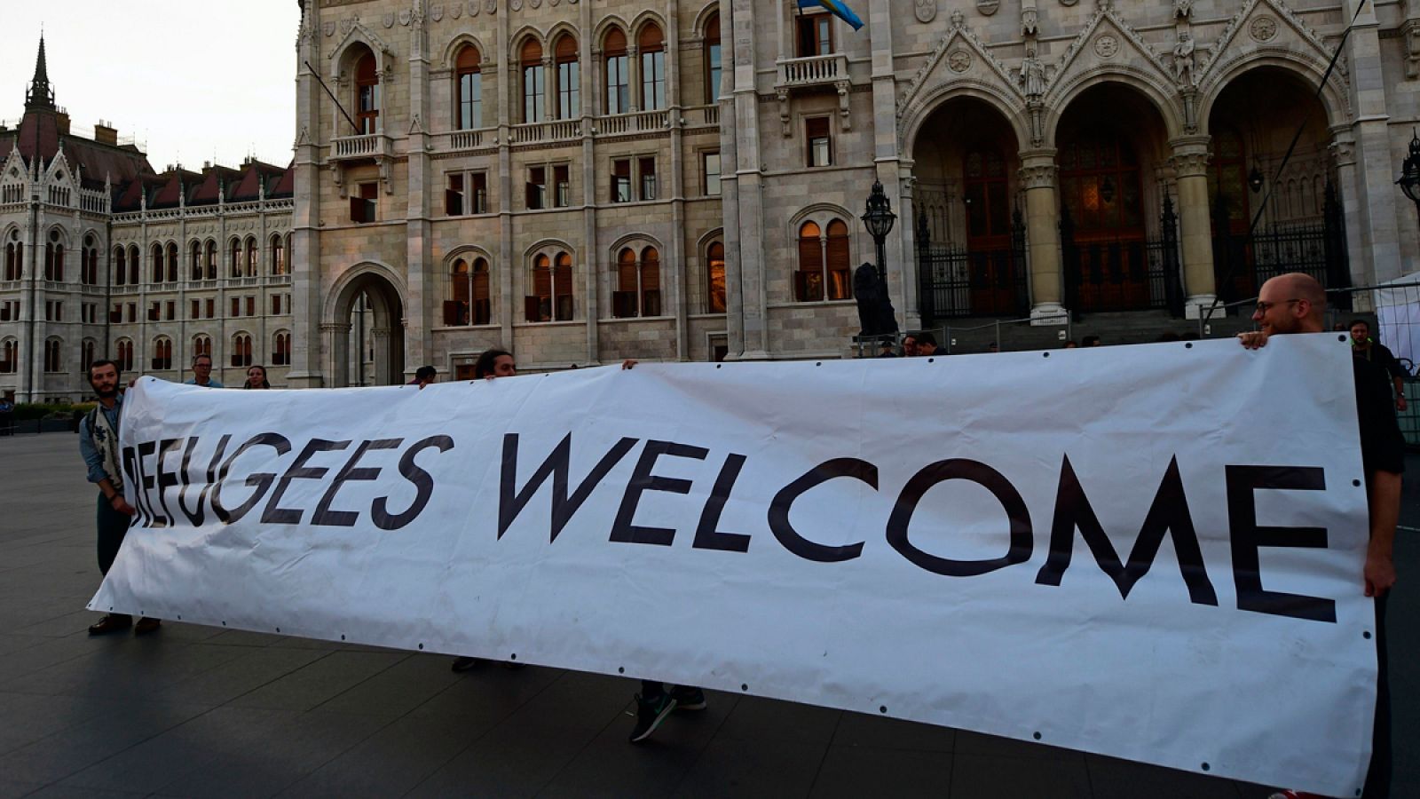 Varios manifestantes sostienen una pancarta en la que se puede leer "Bienvenidos Refugiados" enfrente del Parlamento en Budapest.