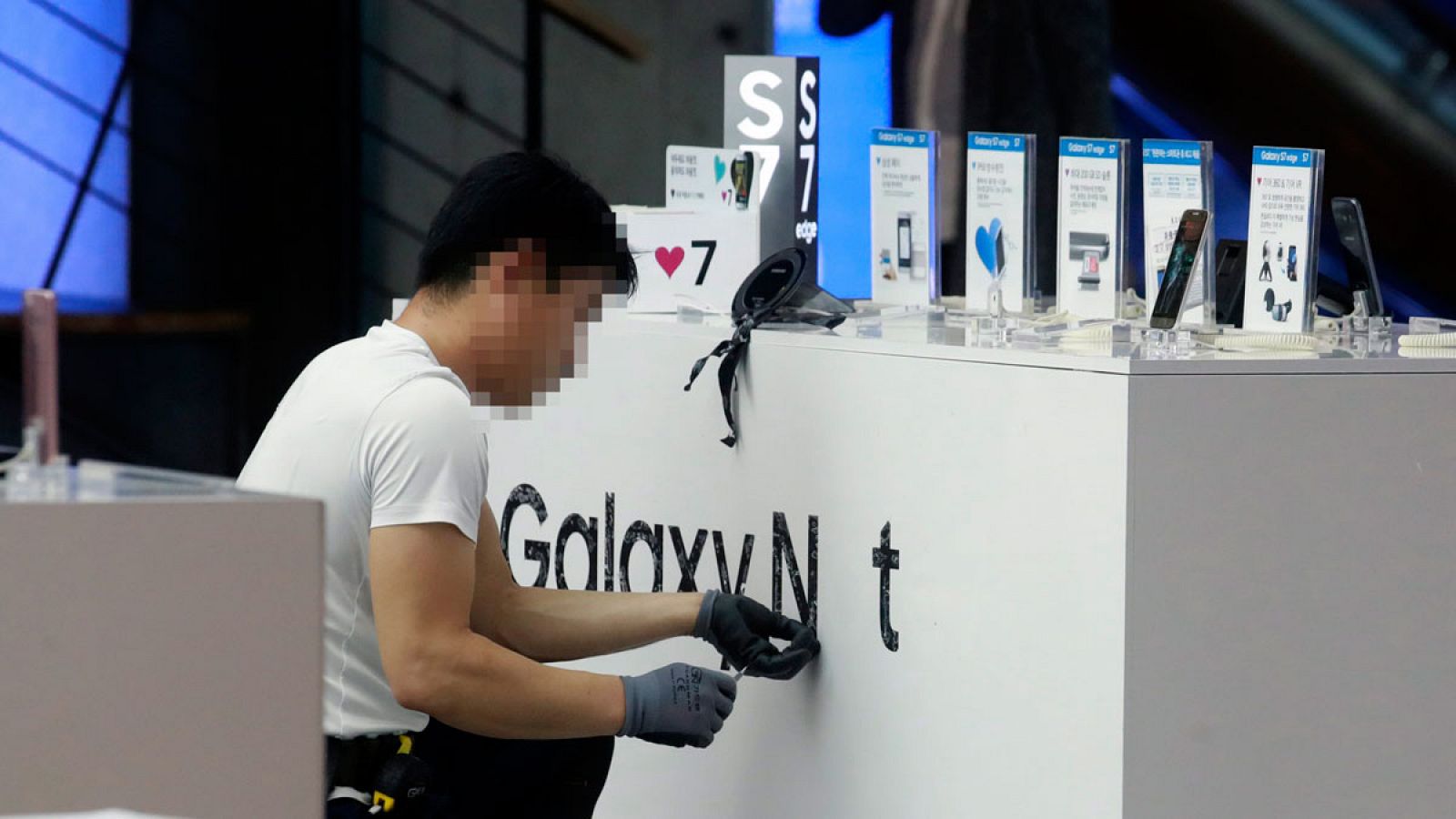 Fotografía del 11 de octubre de 2016 donde se ve a un empleado quitando las marca publicitaria de Galaxy Note 7 de la empresa Samsung Electronic en una tienda en Seúl.