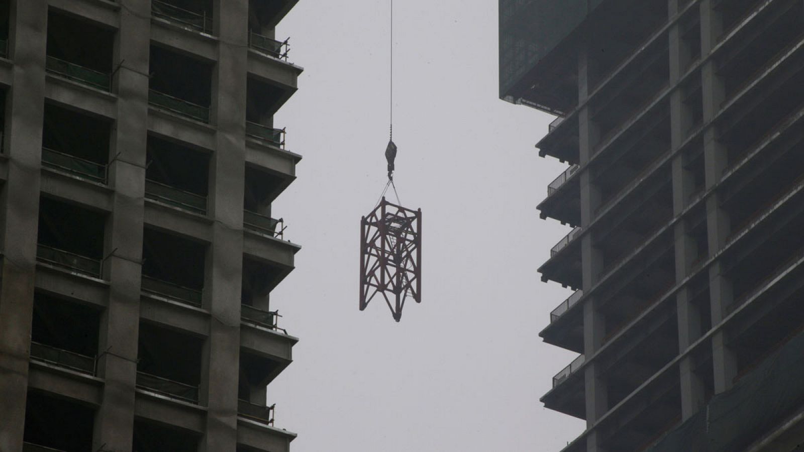 Una grúa suspendida entre dos edificios en construcción de Pekín