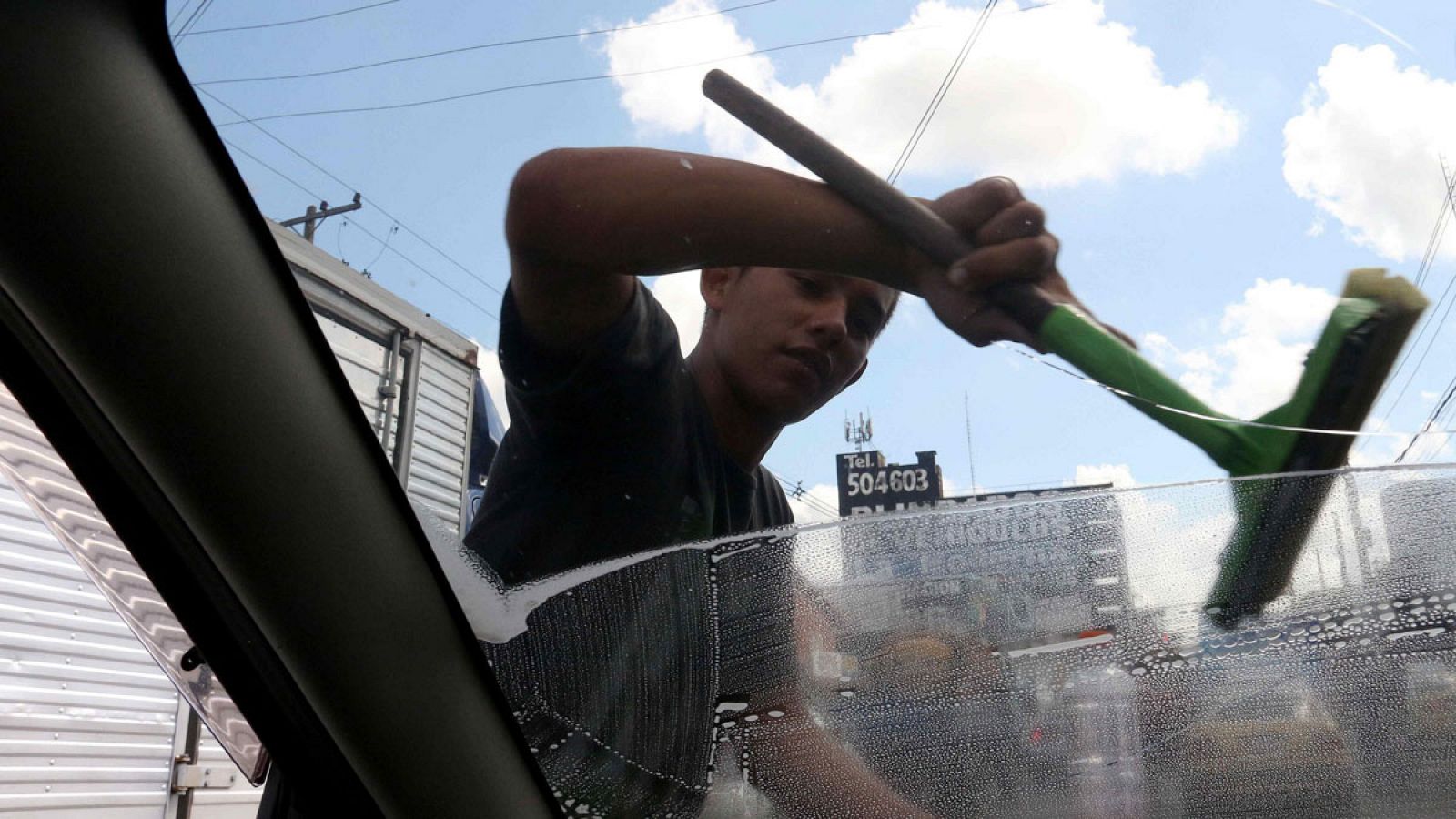 Un joven limpia el parabrisas de un vehículo en una calle de Asunción (Paraguay).
