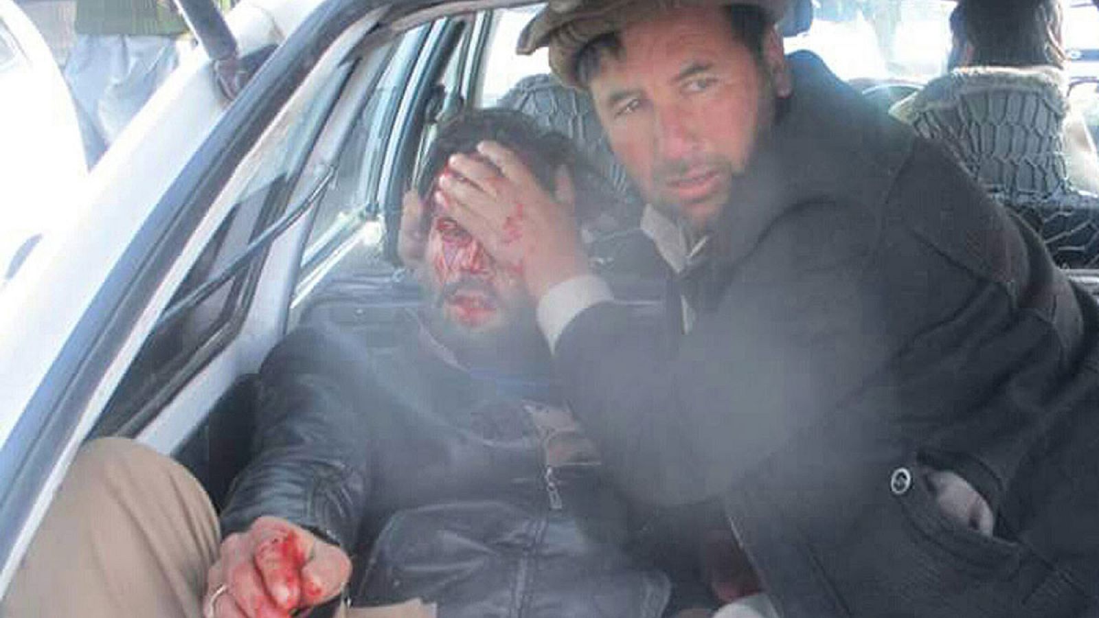 Un hombre ayuda a uno de los heridos en el atentado en el mercado de Pakistán