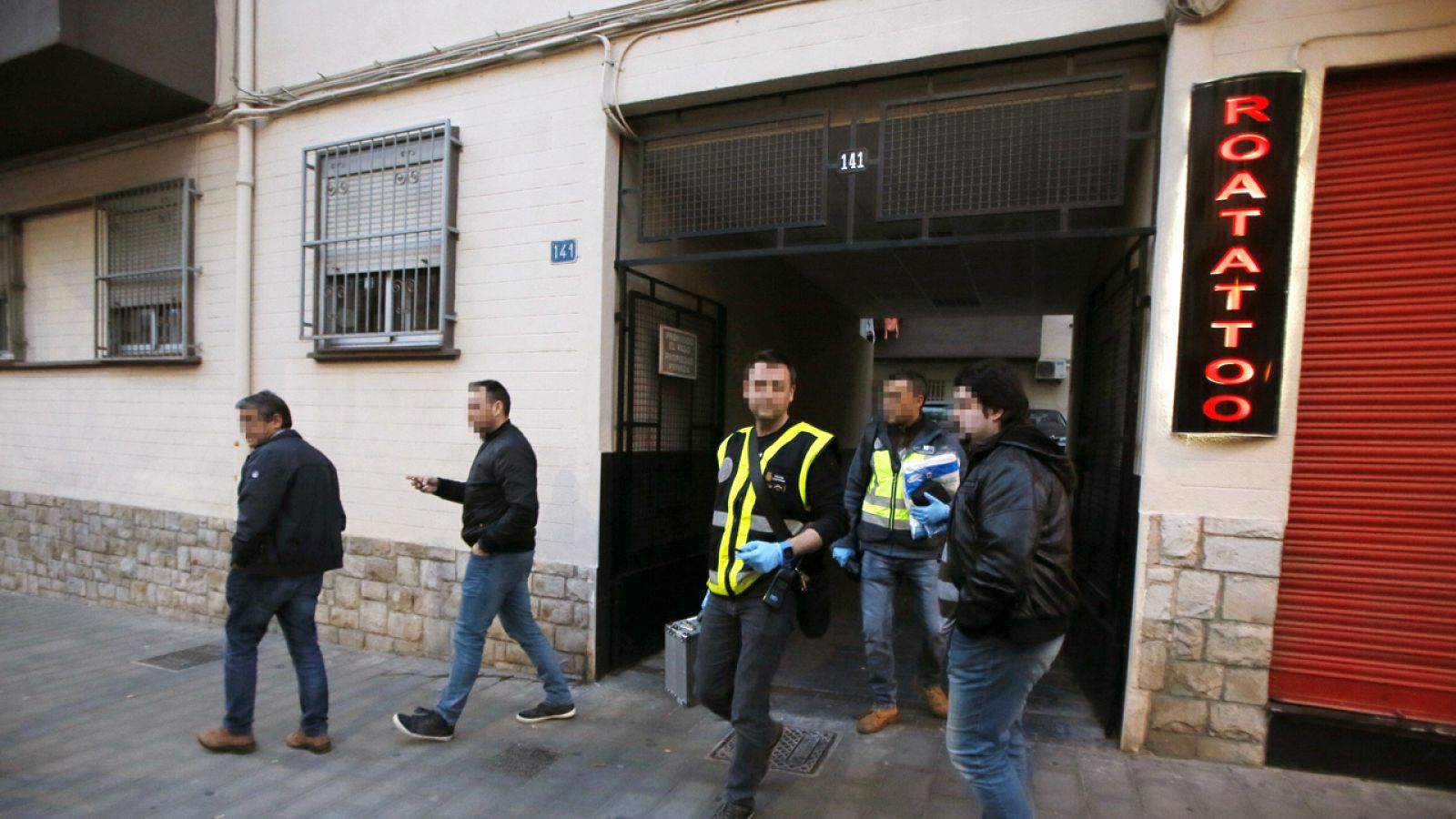 Miembros de la Policía Científica salen del interior del edificio donde una pareja y su hija menor han muerto por asfixia tras caerles encima la ropa que tenían acumulada en casa.