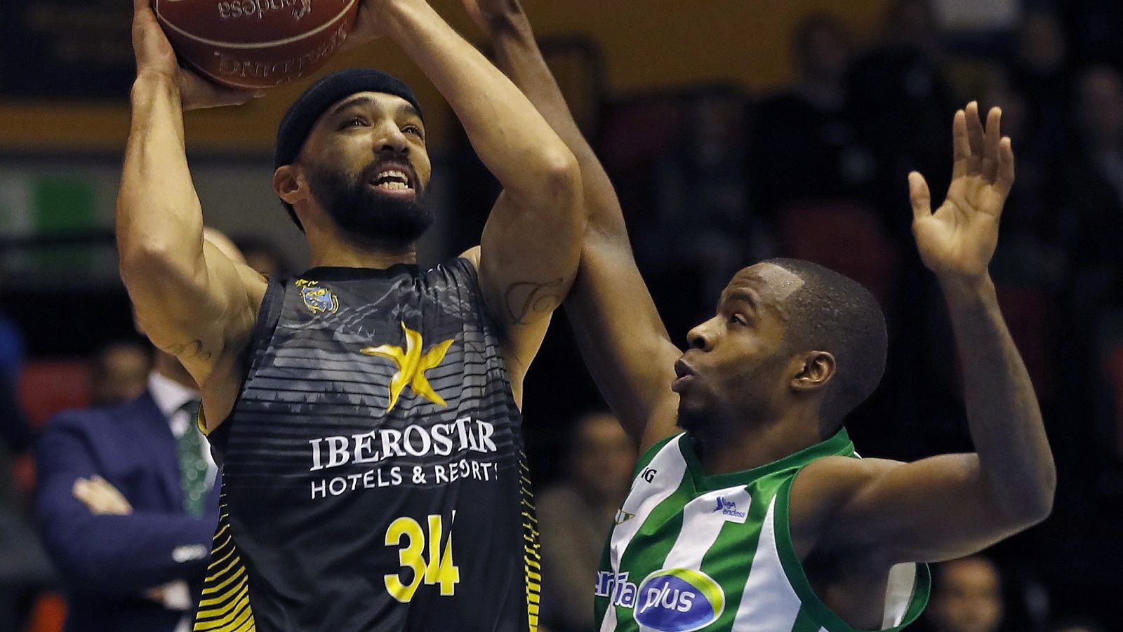 El base estadounidense de Iberostar Tenerife, Davin White, entra a canasta ante el jugador canadiense del Real Betis Energia Plus, Kenny Chery.