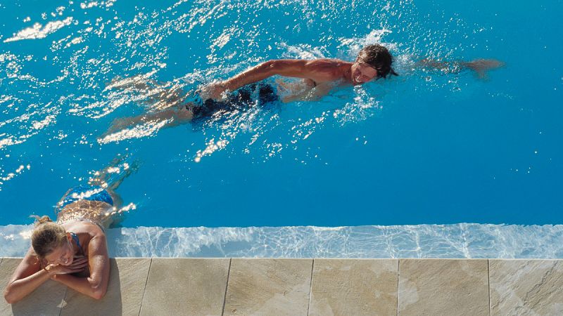 Un hombre y una mujer nadan en una piscina pública