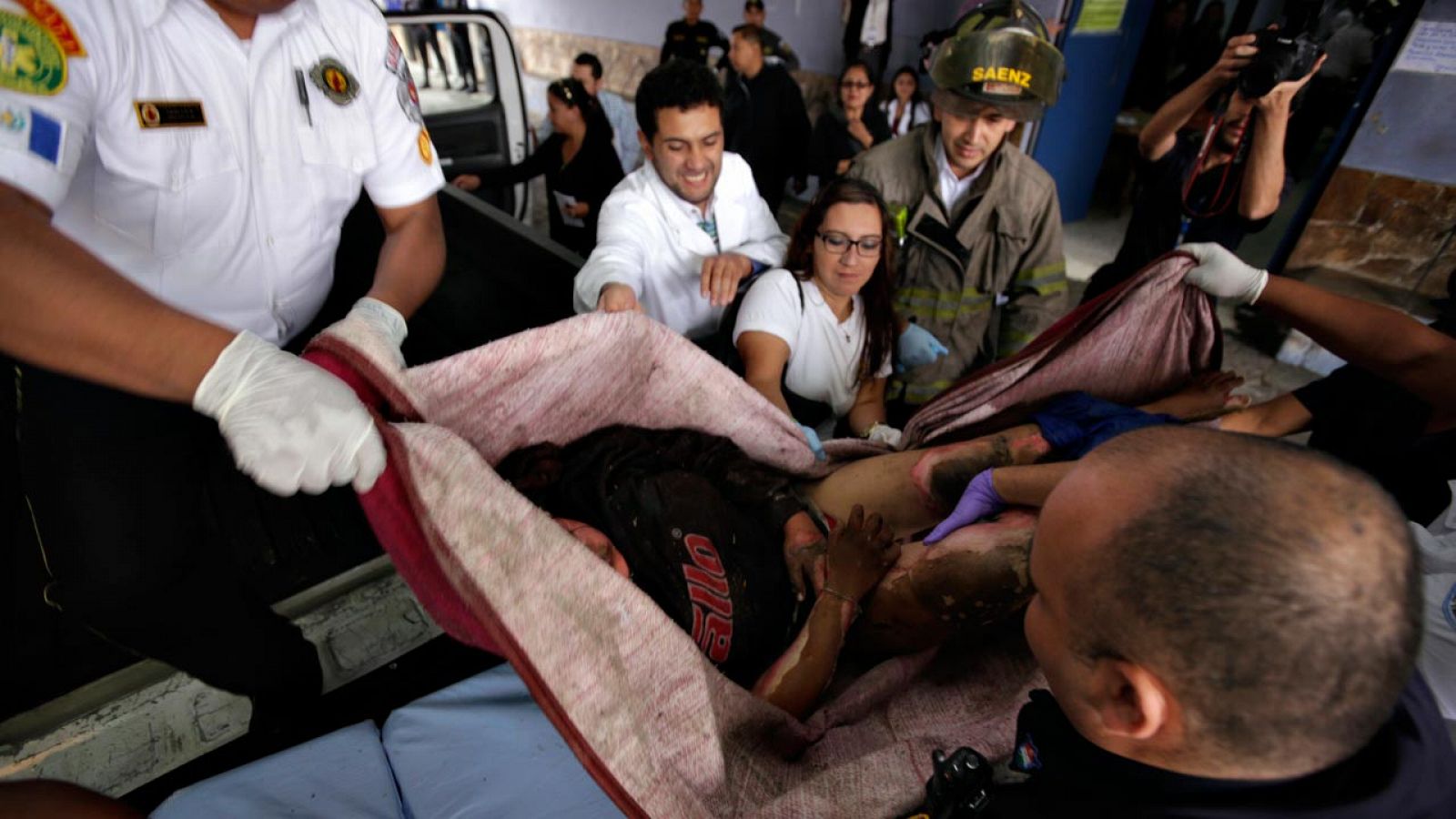 Varios voluntarios colaboran para trasladar a una de las heridas en el incendio del centro de menores de San José Pinula