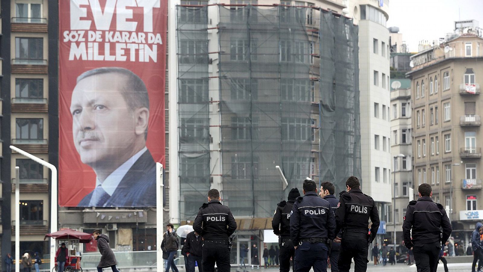 Varias personas caminan junto a un poster con la imagen del presidente turco, Recep Tayyip Erdogan, en la plaza Taksim de Estambul, Turquía, el 14 de marzo de 2017.