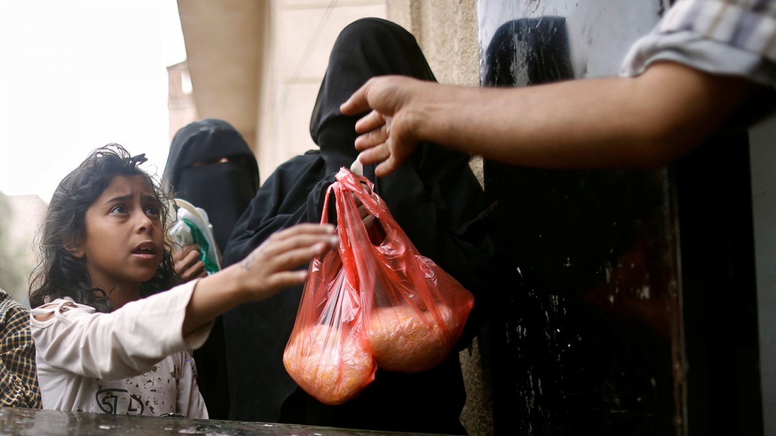 Una niña recibe una ración de arroz en un punto de distribución de alimentos en Saná.