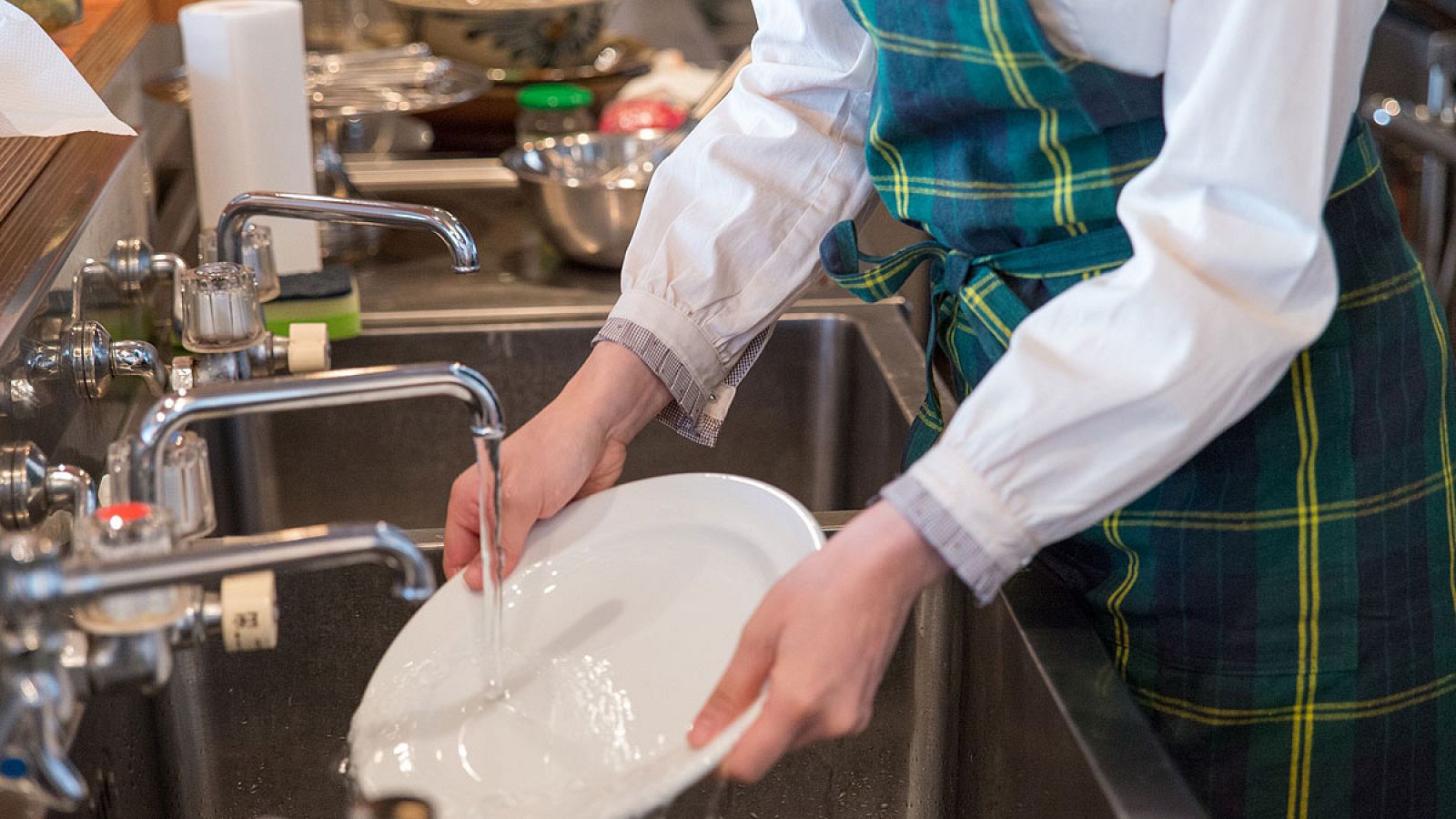 Una empleada friega los platos en un resturante