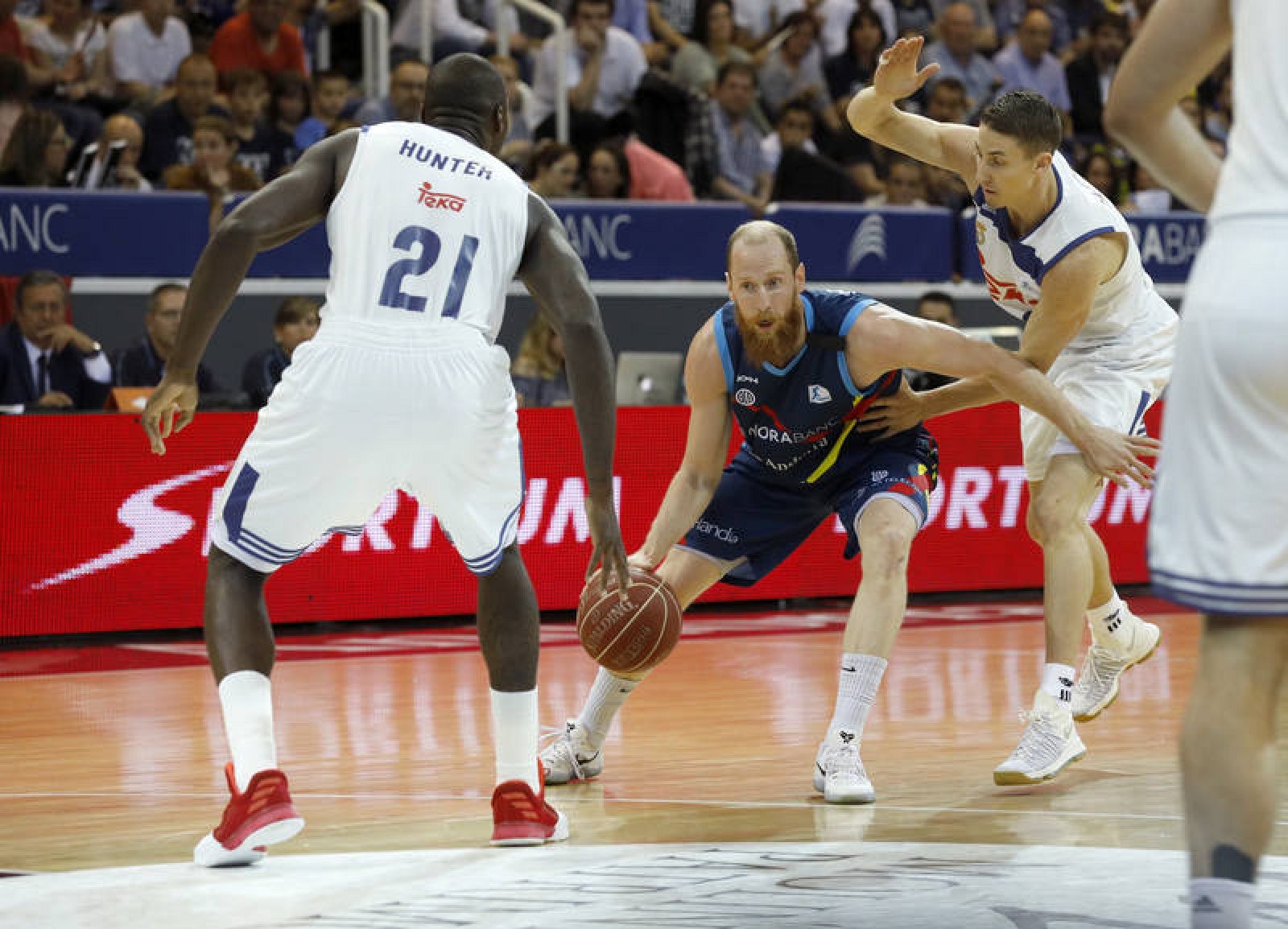 El base Thomas Schreiner  intenta superar a dos jugadores del Real Madrid