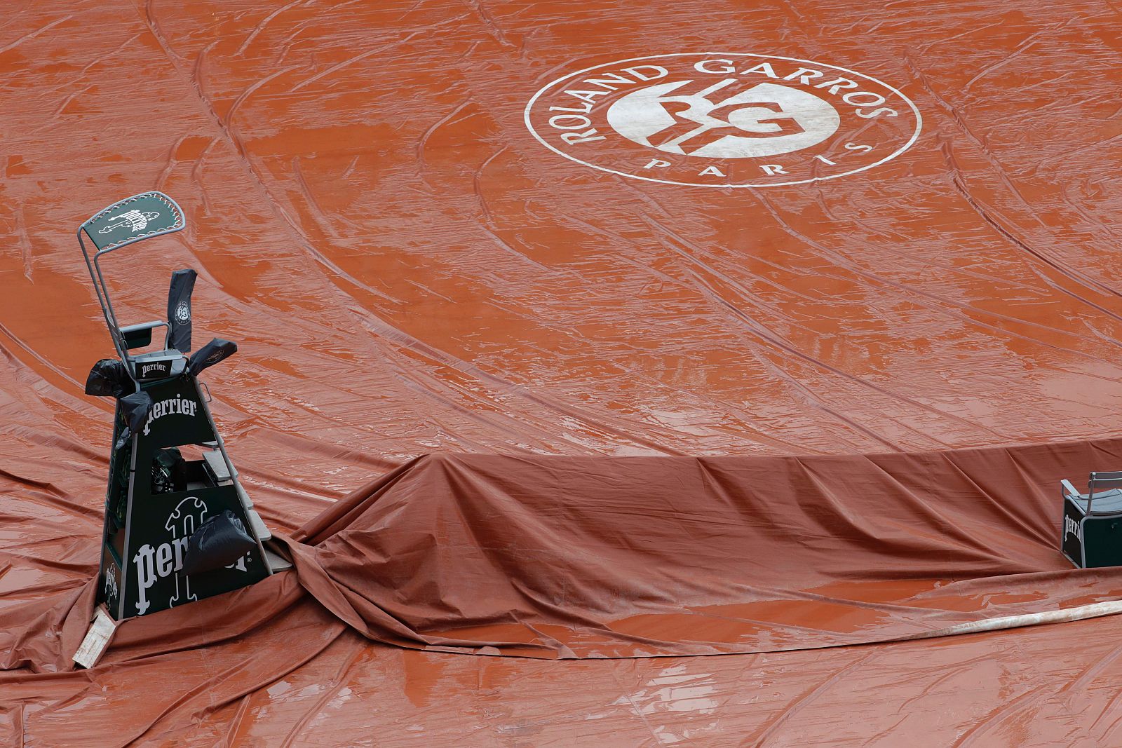 Los operarios tapando la arcilla de la pista central de Roland Garros.