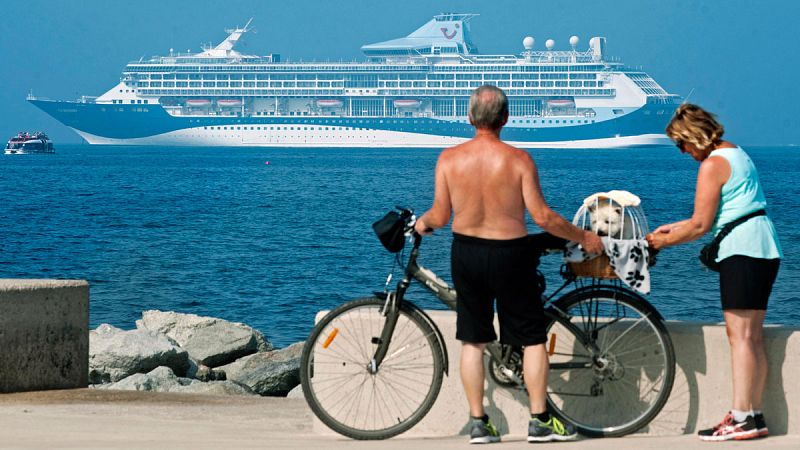 Una pareja observa un crucero en el puerto de Roses, en Girona