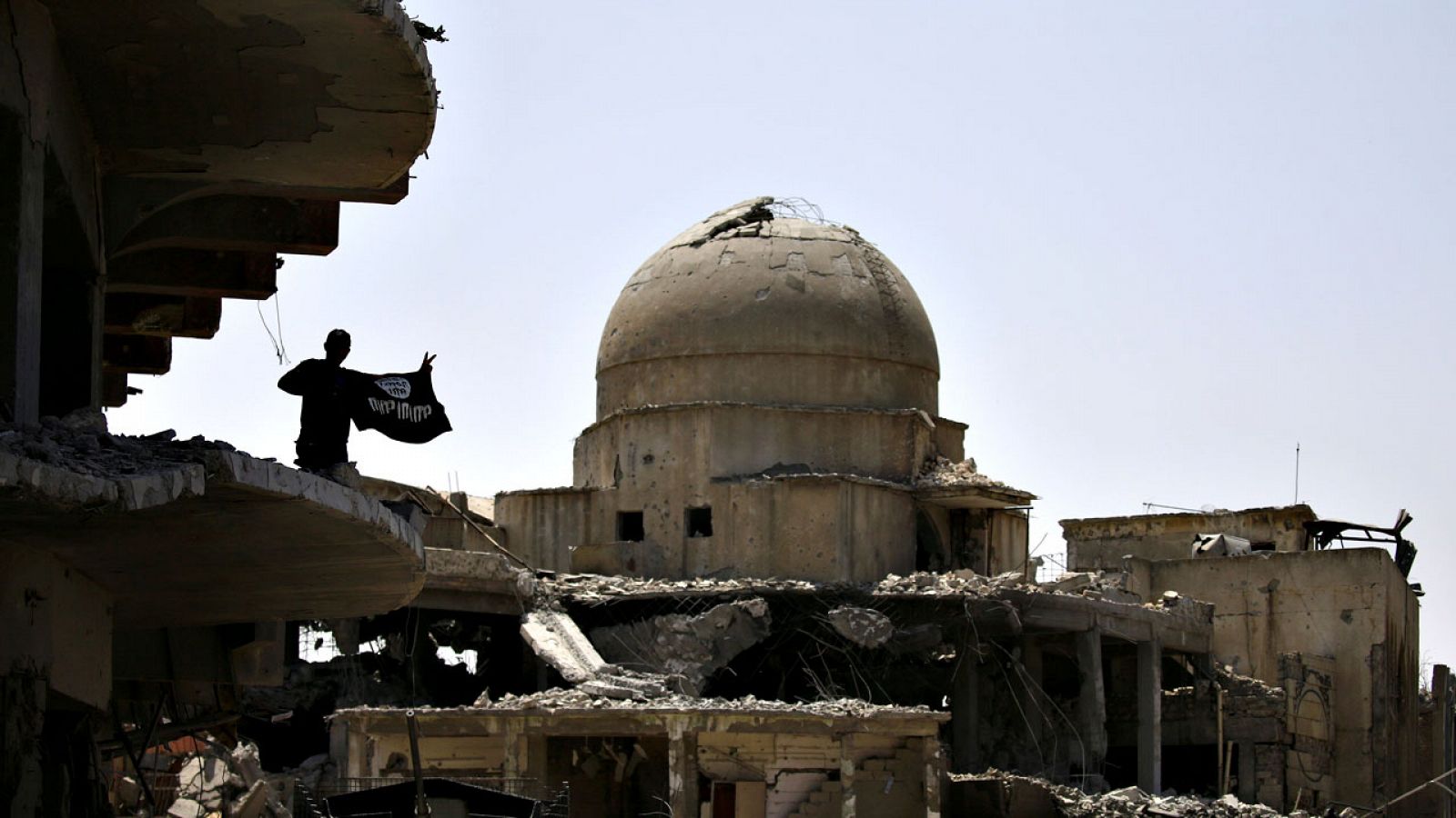 Un soldado iraquí muestra una bandera arrebatada al Estado Islámico en las ruinas del centro de Mosul