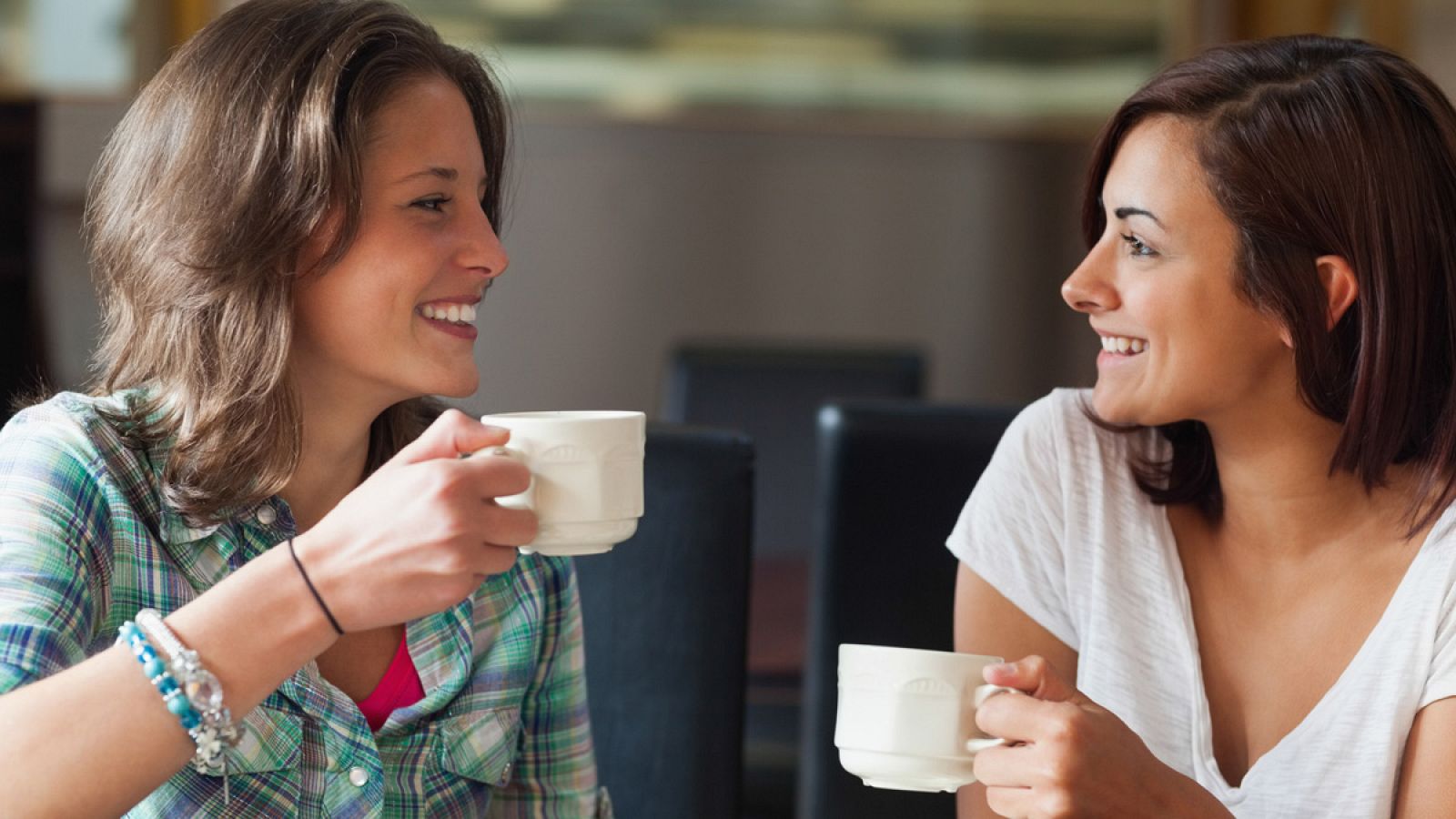 Dos chicas jóvenes conversan mientras toman un café