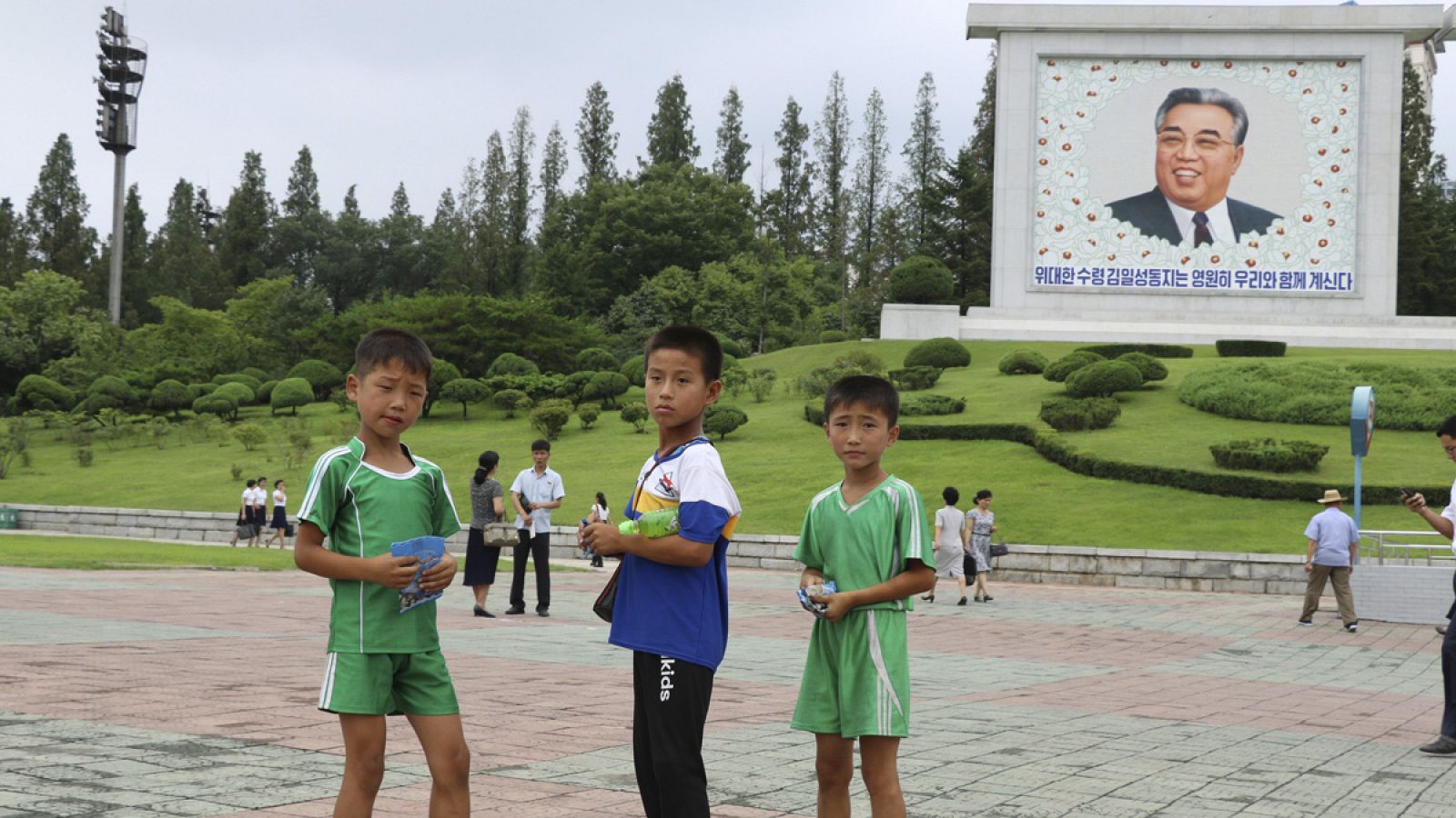 Tres niños delante de un mosaico del líder y fundador del país Kim Il sung en la avenida Mansudae