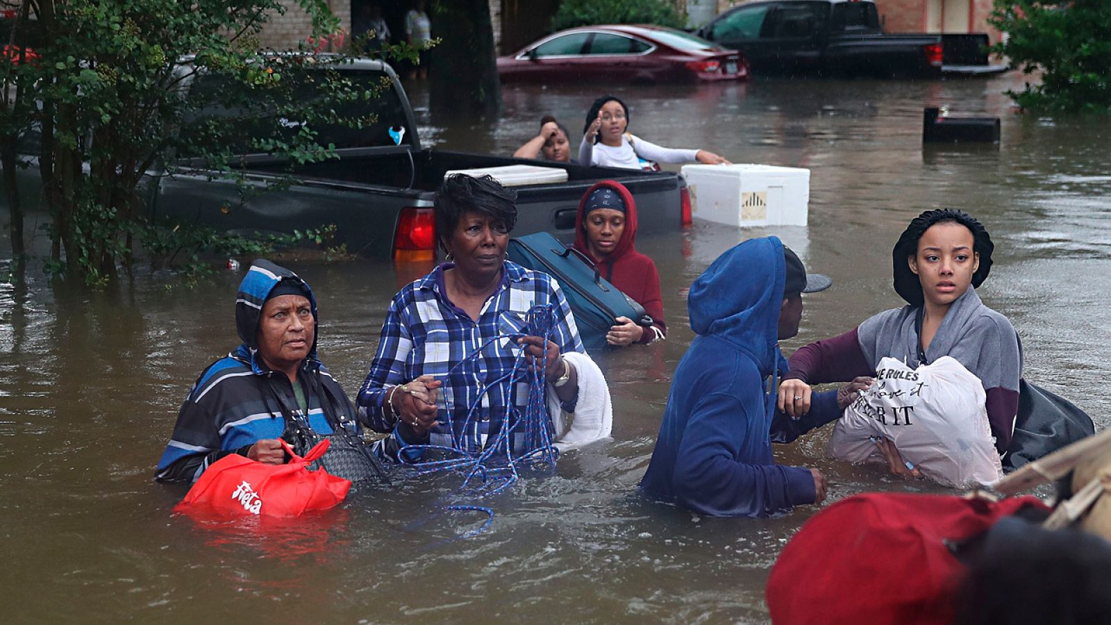 Varios residentes tratan de ponerse a salvo en una calle inundada de Houston por el paso de 'Harvey'