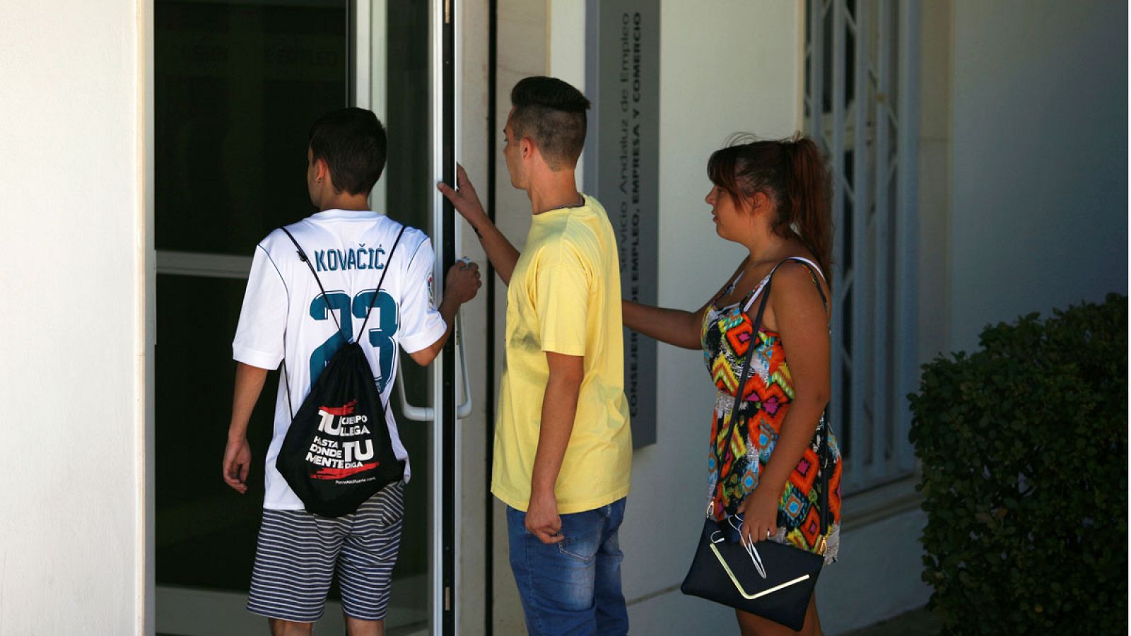 Tres jóvenes se disponen a entrar en una oficina de empleo en Ronda