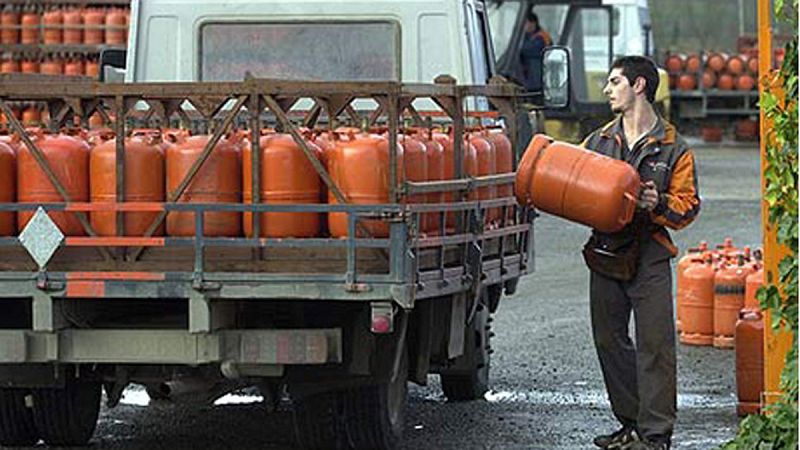 Un repartidor de bombonas de butano carga su camión en un almacén