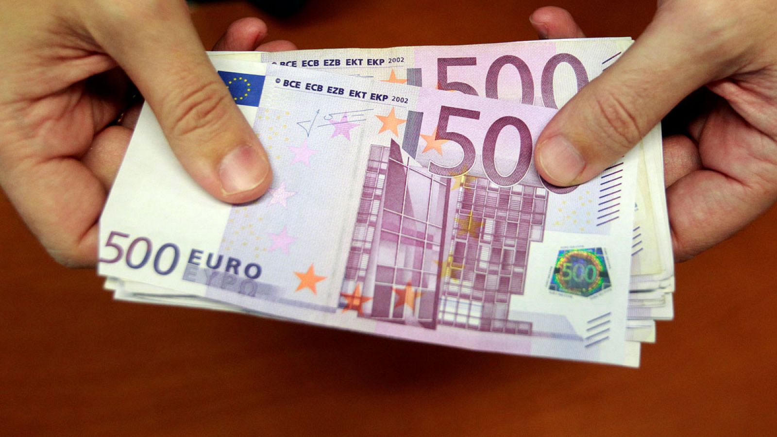 Un empleado de banca muestra varios billetes de 500 euros