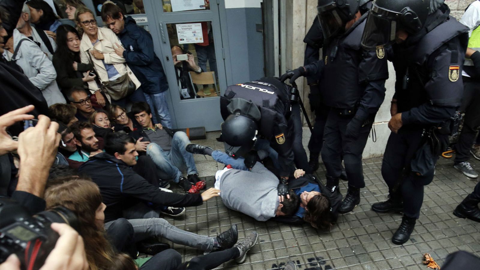 Agentes de Policía Nacional inmovilizan a dos personas en el exterior de un colegio electoral en Barcelona