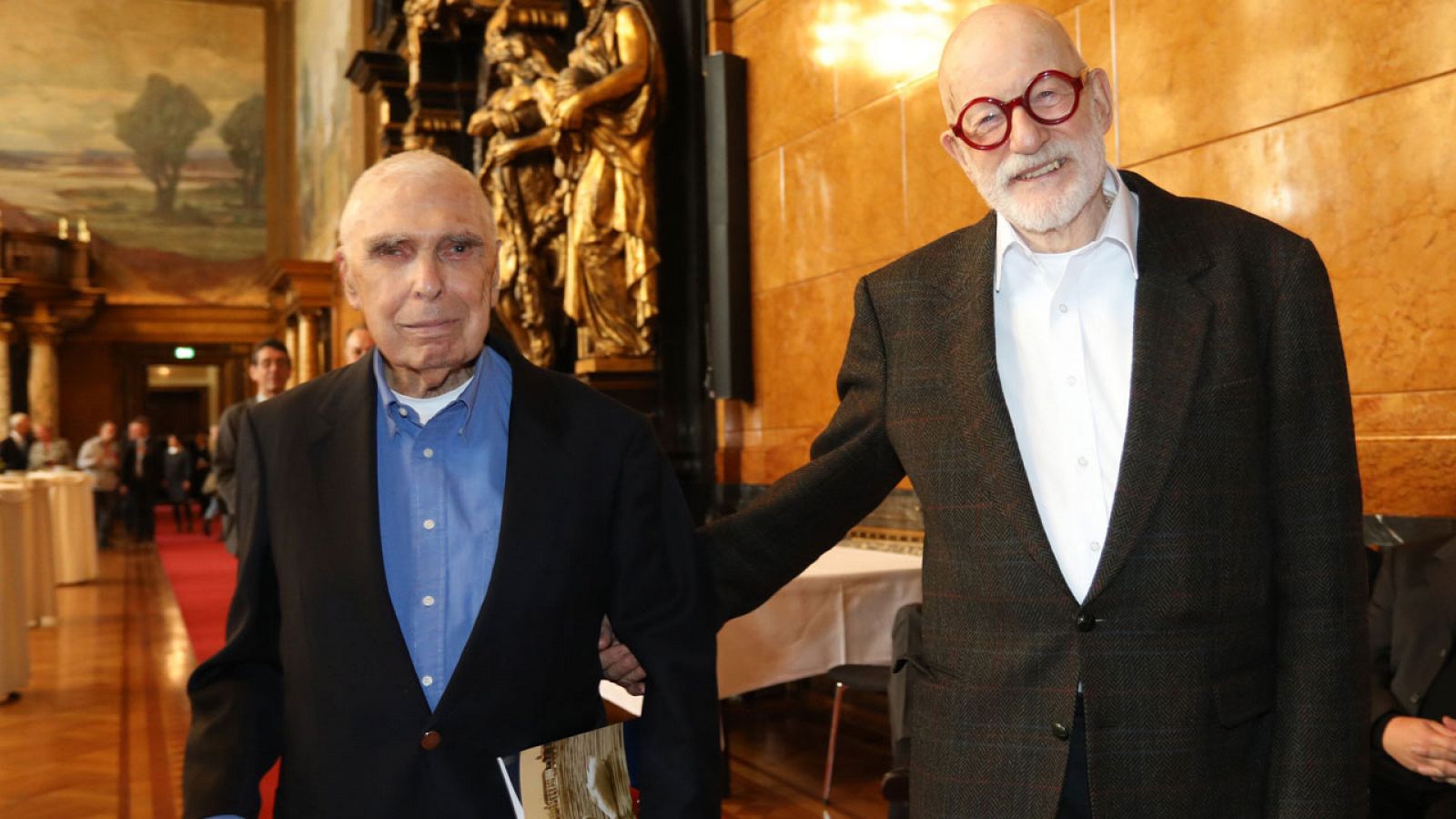 Recién casados, Alfred Kaine y John Guenther caminan sonriendo después de la ceremonia