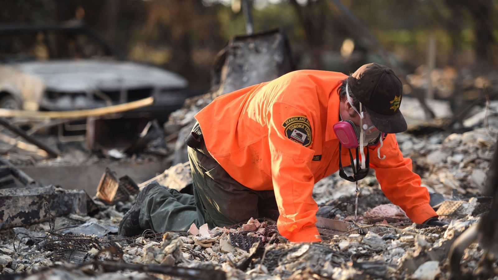 Un miembro de los equipos de rescate busca víctimas entre los restos del incendio en California